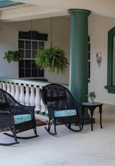 a porch with two chairs and a table